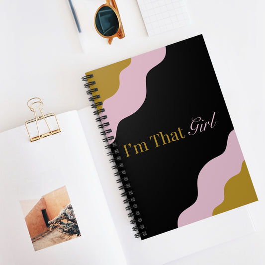 Notebook with 'I'm That Girl' design on a white surface with sunglasses and a photo clip.