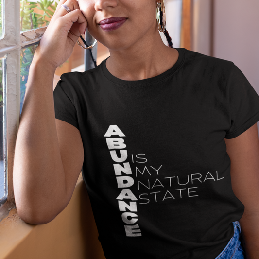 Person wearing a black t-shirt with 'ABUNDANCE IS MY NATURAL STATE' text.