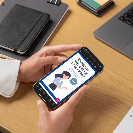 Person holding a smartphone with an app on a desk with notebooks and a laptop.