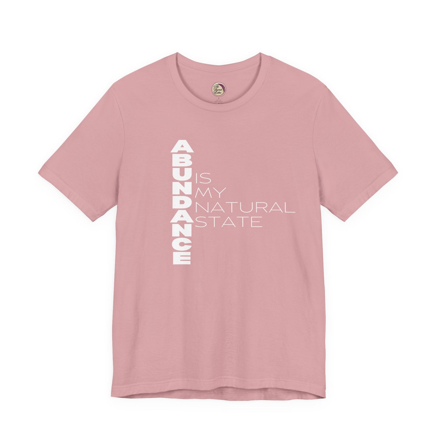 Pink t-shirt with 'Abundance is my natural state' text on a white background