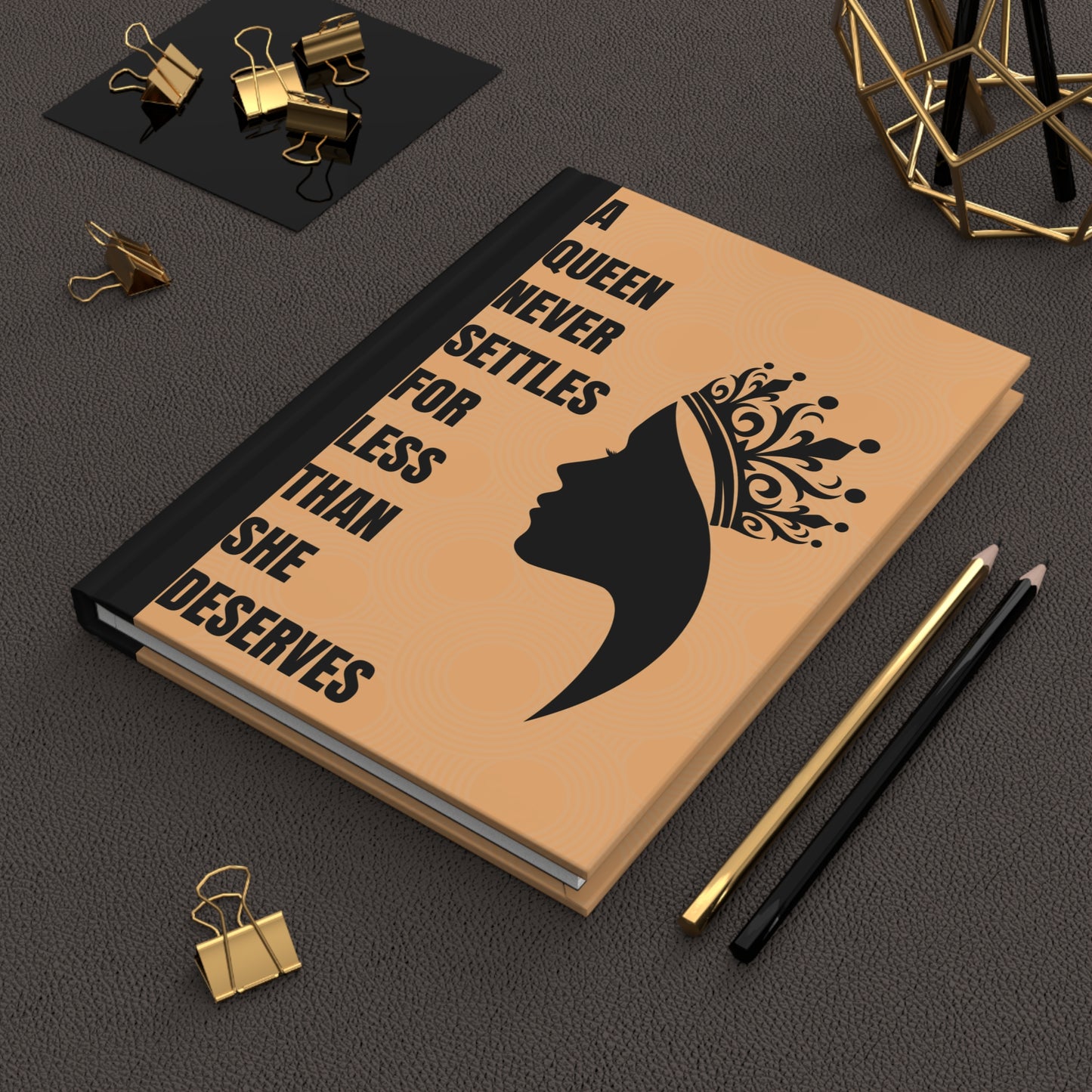 Notebook with motivational quote and silhouette design on a dark surface with office supplies.