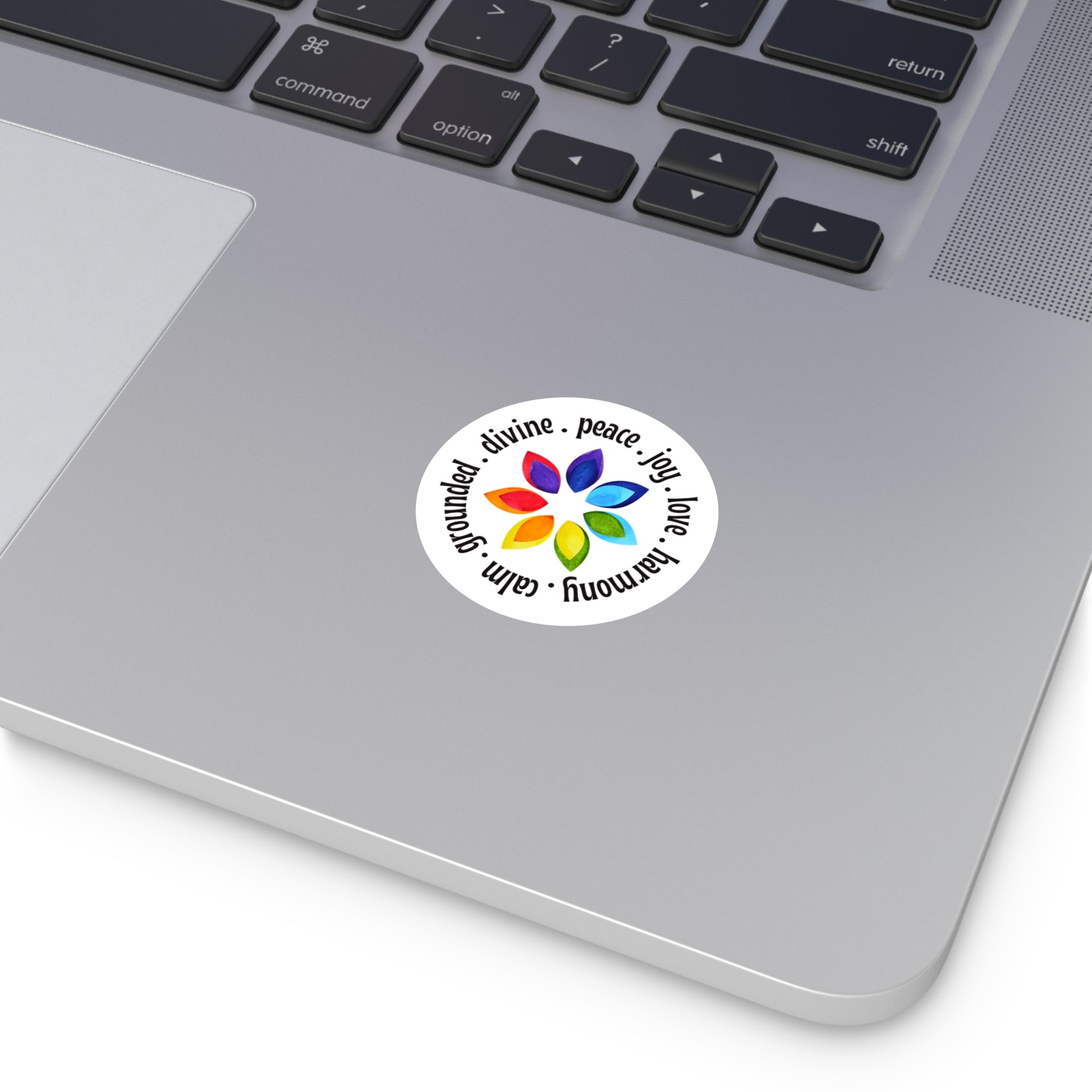 Laptop with a sticker featuring a colorful flower design and text on the palm rest area.