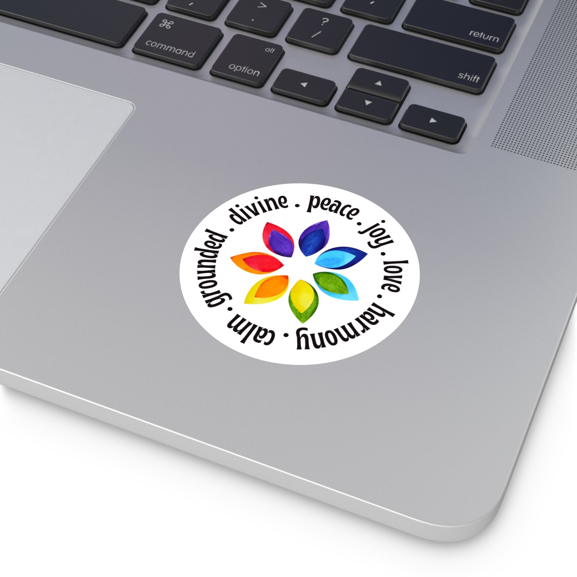 Laptop with a sticker featuring a colorful flower design and text on the palm rest area.