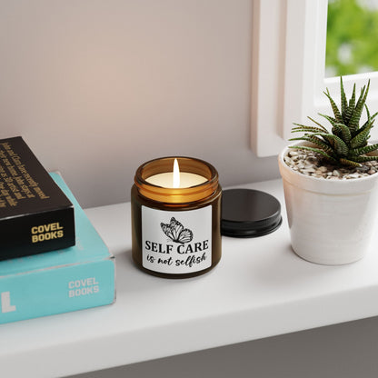 Candle with 'Self care is not selfish' label on a shelf with books and a plant