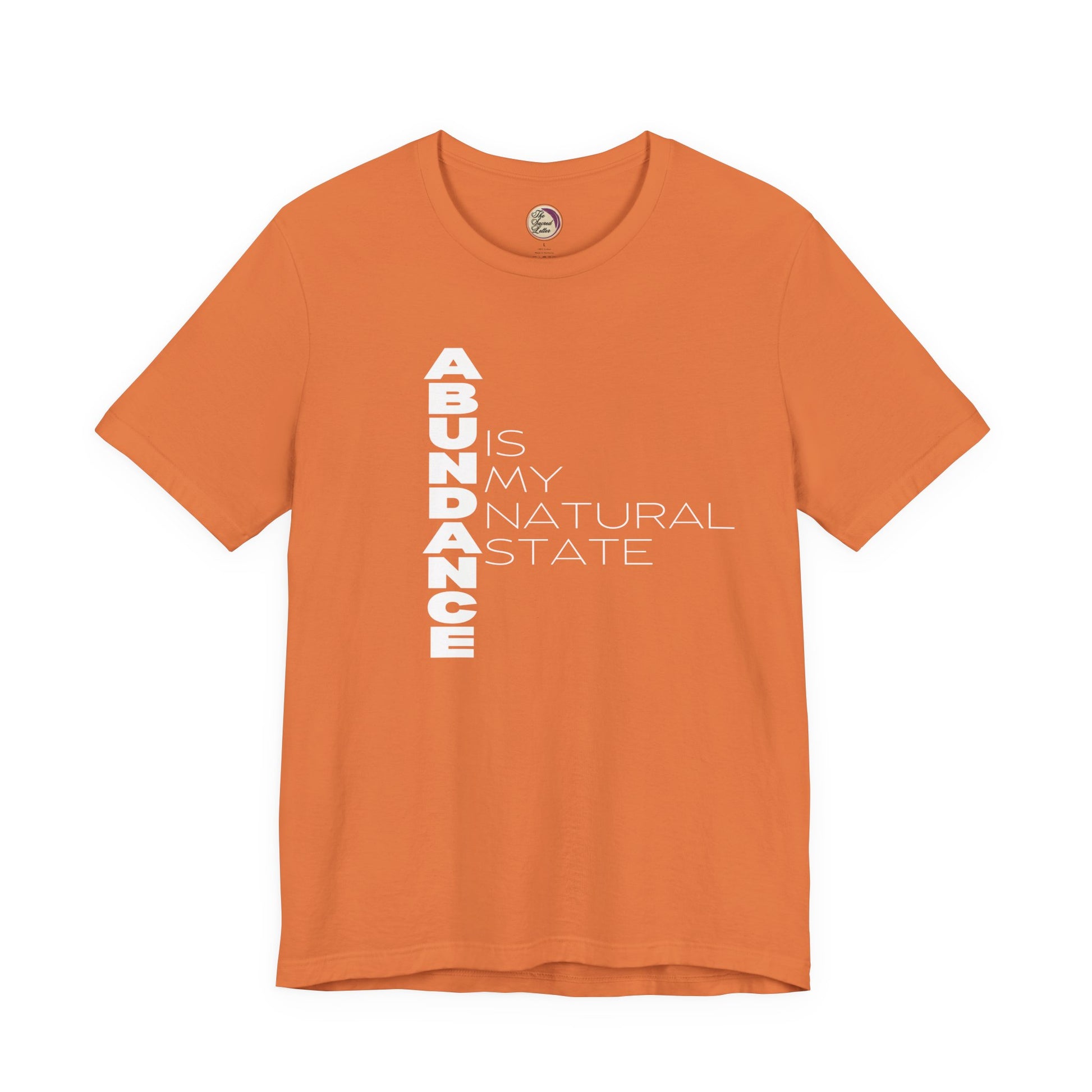 Orange t-shirt with white text 'ABUNDANCE IS MY NATURAL STATE' on a white background