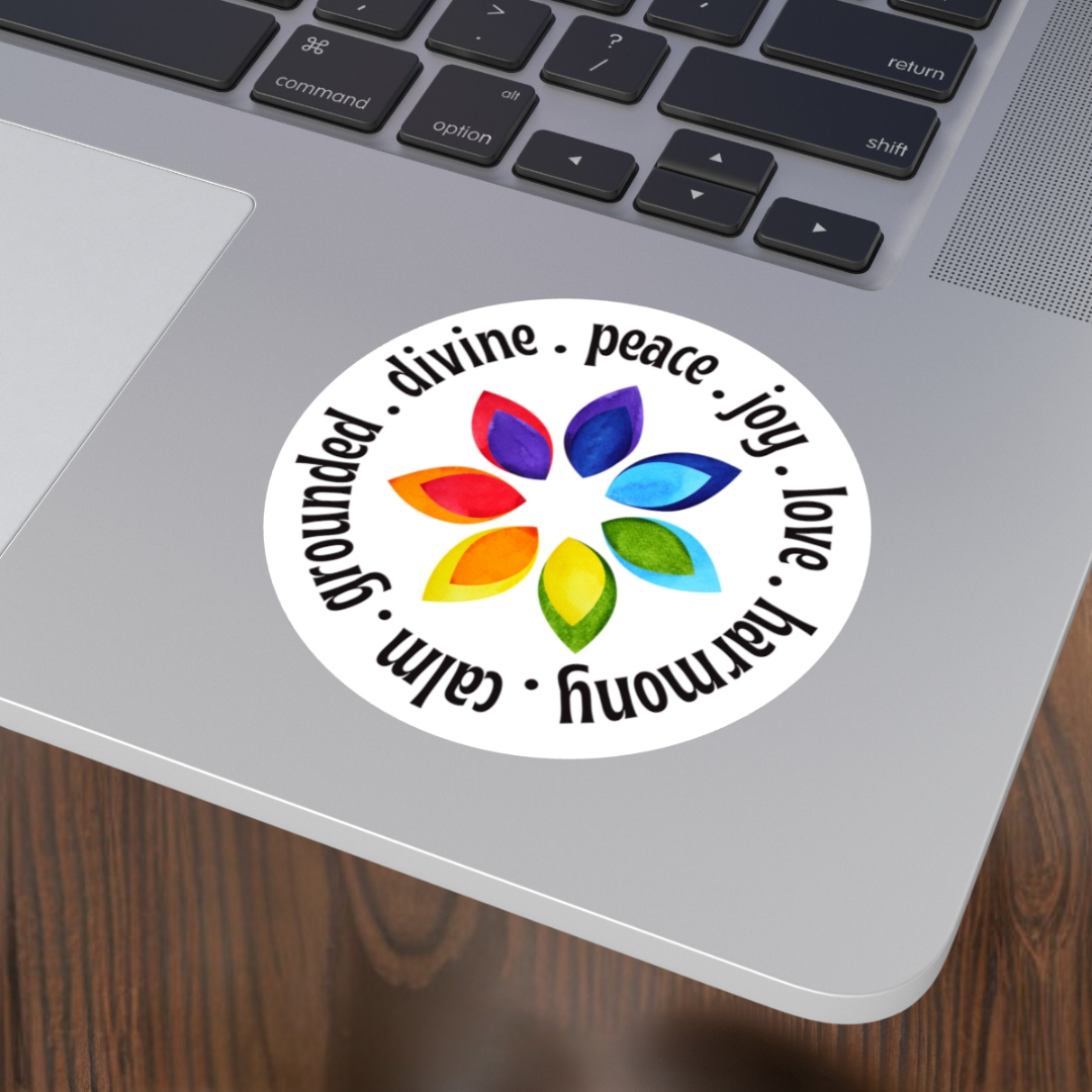 Laptop with a colorful sticker featuring a rainbow flower design and motivational words on a wooden surface.