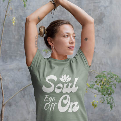 Woman wearing a green t-shirt with 'Soul Ego Off On' text against a gray wall.