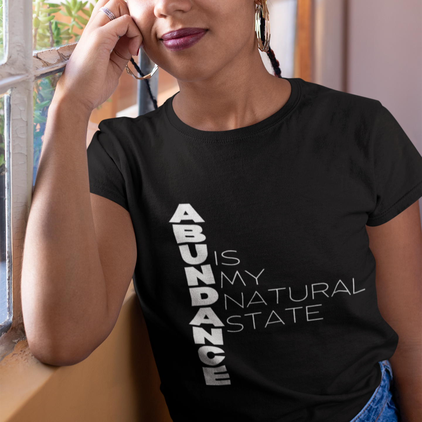 Person wearing a black t-shirt with 'ABUNDANCE IS MY NATURAL STATE' text.