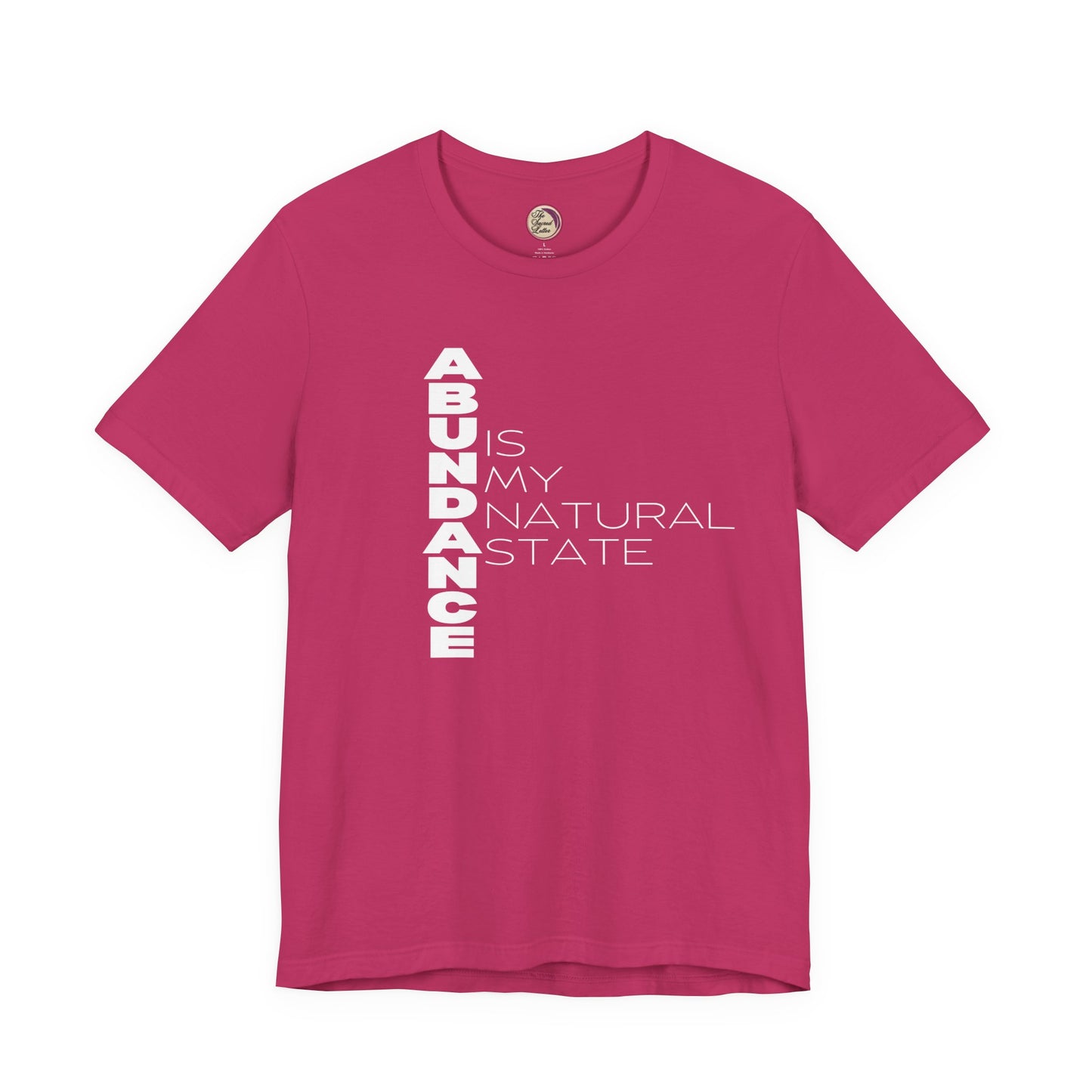 Pink t-shirt with white text 'ABUNDANCE IS MY NATURAL STATE' on a white background